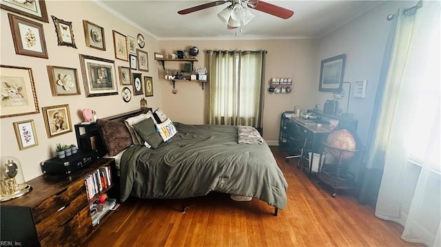 bedroom with ceiling fan, crown molding, and wood-type flooring