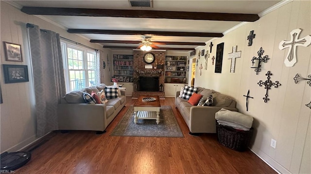 living room featuring a brick fireplace, ornamental molding, ceiling fan, dark wood-type flooring, and beam ceiling