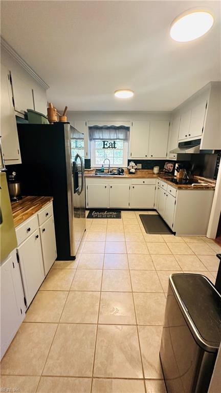 kitchen featuring stainless steel refrigerator, white cabinetry, sink, and light tile patterned flooring