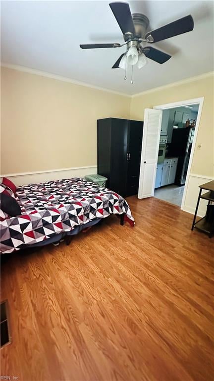 unfurnished bedroom with black refrigerator, light wood-type flooring, ceiling fan, and crown molding