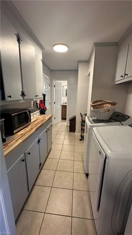 laundry area with washer and dryer, light tile patterned floors, and ornamental molding