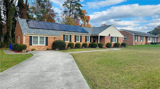 ranch-style home with solar panels and a front lawn