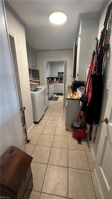 kitchen featuring washer and clothes dryer, light tile patterned flooring, white cabinets, and ornamental molding