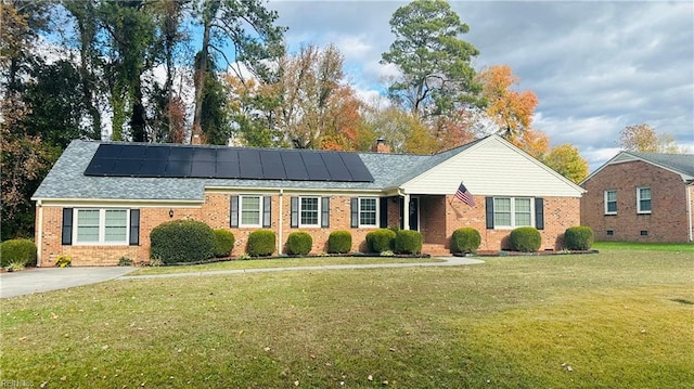 ranch-style home featuring solar panels and a front lawn