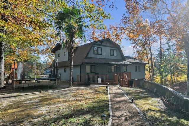 rear view of house with a trampoline and a wooden deck