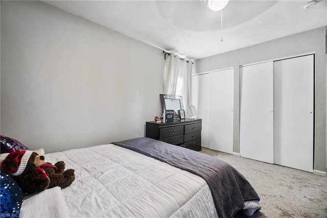 carpeted bedroom featuring two closets and ceiling fan