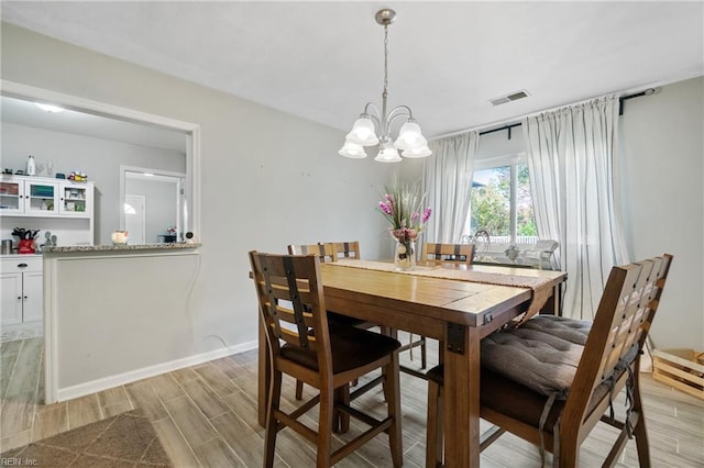 dining space with light hardwood / wood-style flooring and a notable chandelier