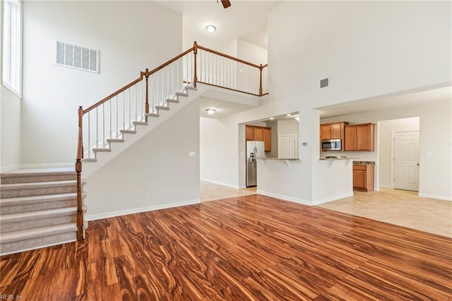 unfurnished living room with a towering ceiling and light hardwood / wood-style floors