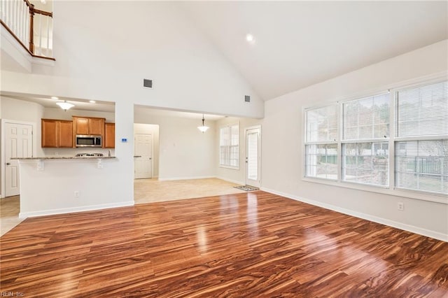 unfurnished living room featuring light wood-type flooring and high vaulted ceiling