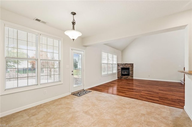 unfurnished living room with lofted ceiling, light hardwood / wood-style flooring, and a stone fireplace