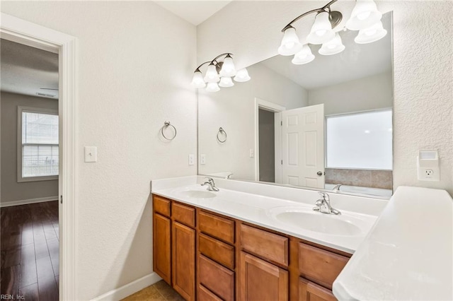 bathroom featuring hardwood / wood-style floors, vanity, a tub to relax in, and a notable chandelier