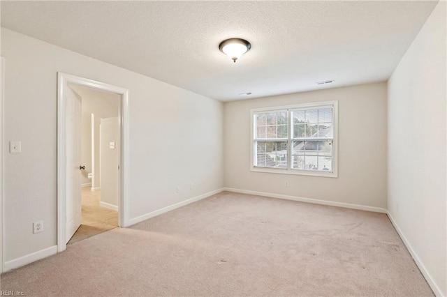 empty room with light carpet and a textured ceiling