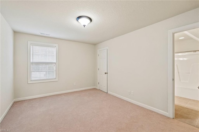 empty room featuring light colored carpet and a textured ceiling