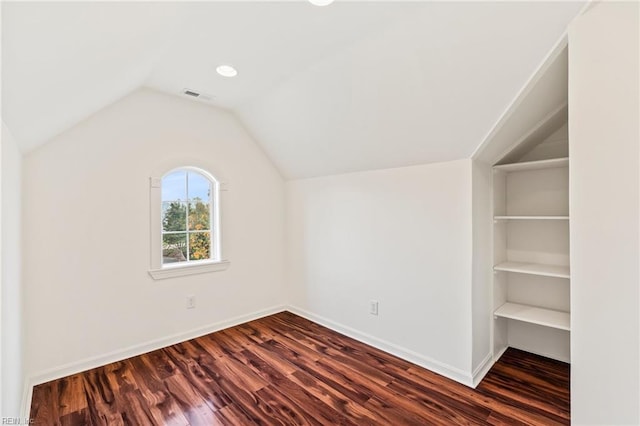 additional living space with built in shelves, dark wood-type flooring, and vaulted ceiling