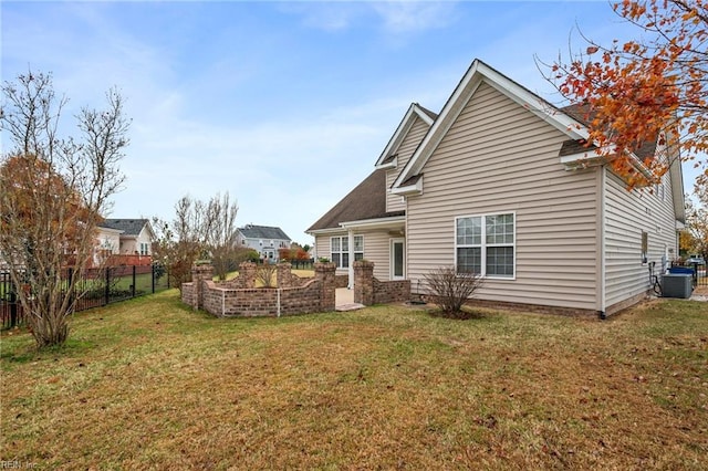 rear view of house with central AC and a lawn