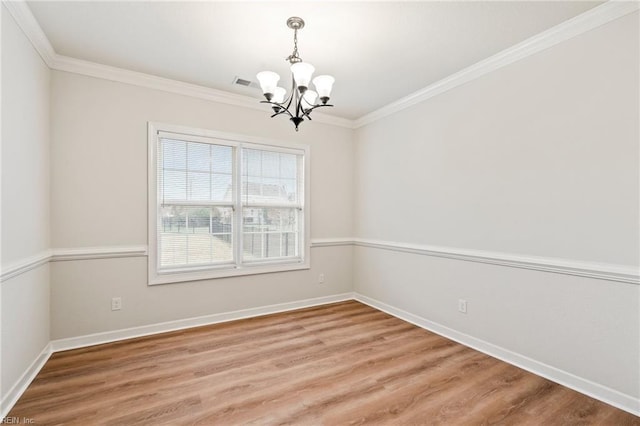 spare room with hardwood / wood-style floors, ornamental molding, and an inviting chandelier