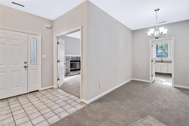 entryway featuring light carpet, a fireplace, a notable chandelier, and sink