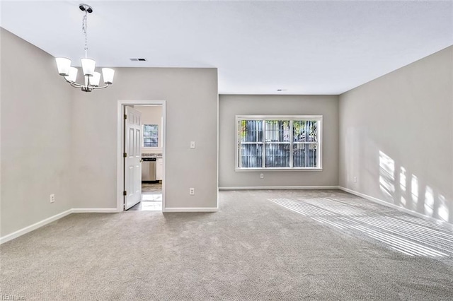 carpeted empty room with an inviting chandelier