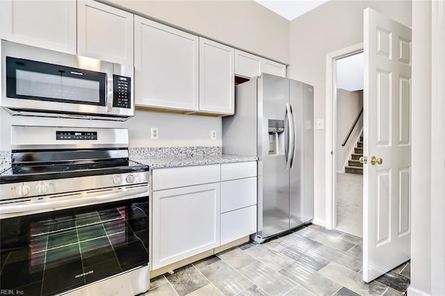 kitchen featuring white cabinets, stainless steel appliances, and light stone countertops