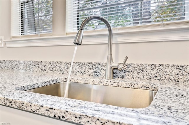 room details featuring light stone countertops and sink