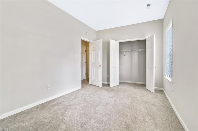 unfurnished bedroom with light carpet and a closet