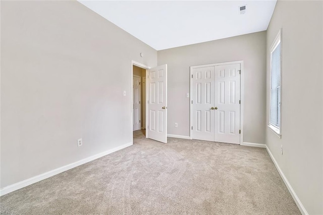 unfurnished bedroom featuring light carpet and a closet