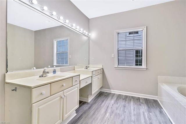 bathroom featuring tiled tub, hardwood / wood-style floors, and vanity