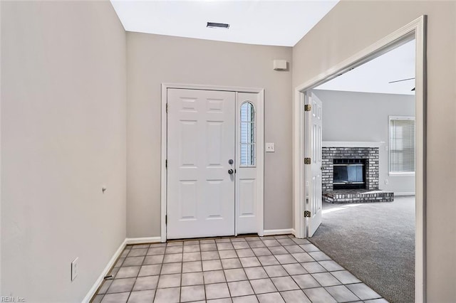 foyer entrance featuring light colored carpet and a fireplace