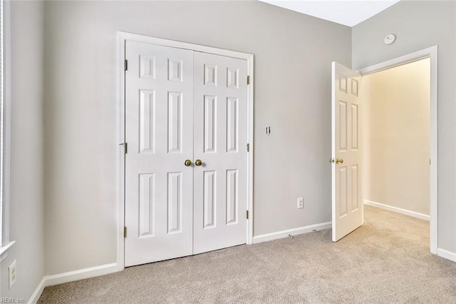 unfurnished bedroom with light carpet and a closet