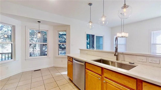 kitchen featuring dishwasher, light tile patterned floors, sink, and decorative light fixtures