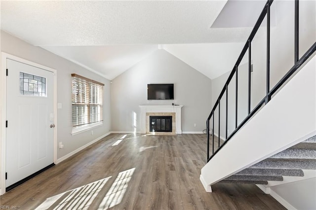 foyer featuring a tiled fireplace, hardwood / wood-style floors, and lofted ceiling