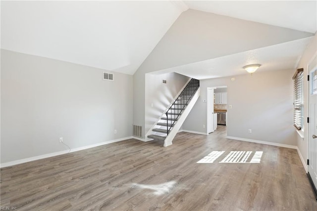 unfurnished living room featuring high vaulted ceiling and light wood-type flooring