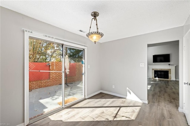 doorway to outside featuring a tile fireplace, hardwood / wood-style floors, and a textured ceiling