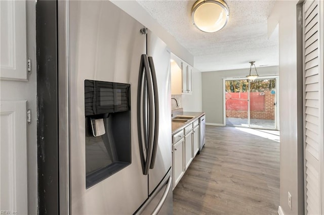 kitchen with sink, light hardwood / wood-style floors, a textured ceiling, white cabinets, and appliances with stainless steel finishes