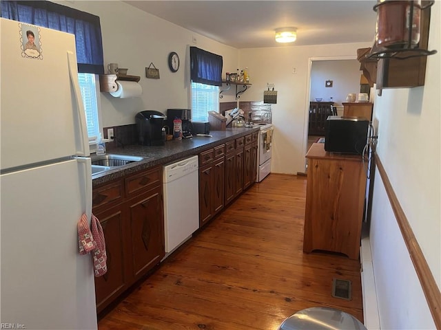 kitchen featuring hardwood / wood-style floors, white appliances, and dark brown cabinetry