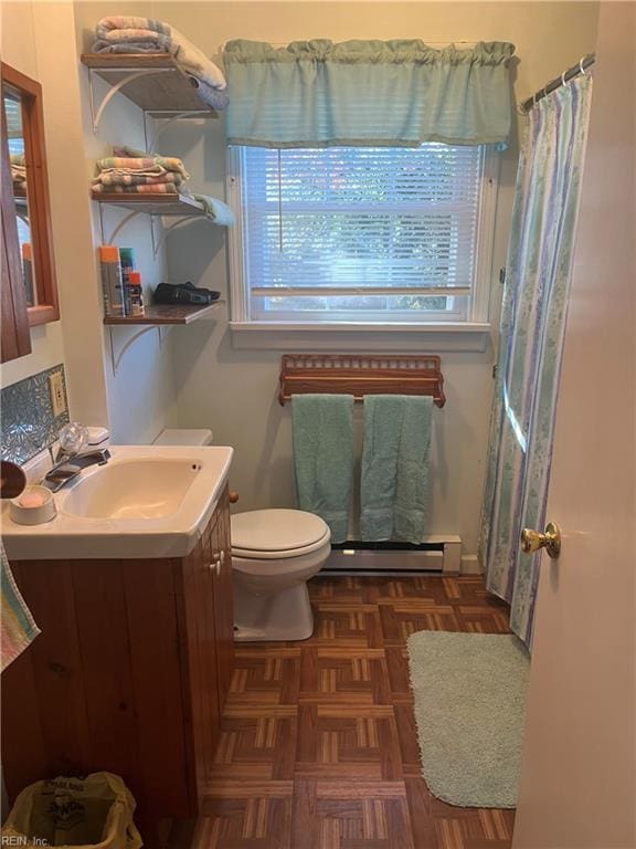 bathroom featuring parquet floors, toilet, baseboard heating, and a healthy amount of sunlight