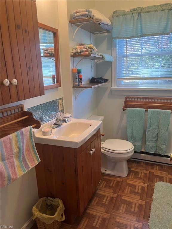 bathroom with vanity, toilet, parquet floors, and baseboard heating