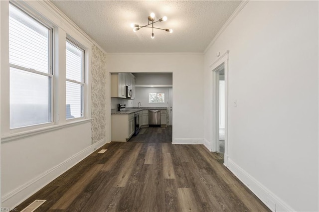 hall featuring a textured ceiling, dark hardwood / wood-style floors, crown molding, and a notable chandelier