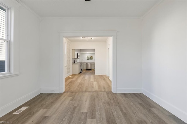 corridor with light wood-type flooring and ornamental molding