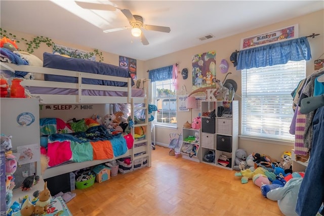 bedroom with ceiling fan, parquet floors, and multiple windows