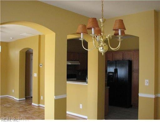 kitchen featuring a chandelier and black refrigerator with ice dispenser