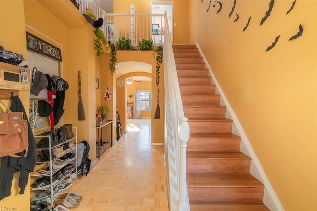 staircase with parquet floors and a towering ceiling