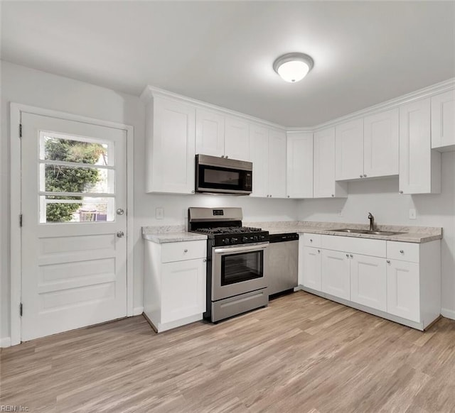 kitchen featuring white cabinets, sink, appliances with stainless steel finishes, and light hardwood / wood-style flooring