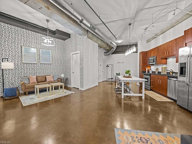 kitchen featuring decorative light fixtures, a towering ceiling, appliances with stainless steel finishes, and track lighting