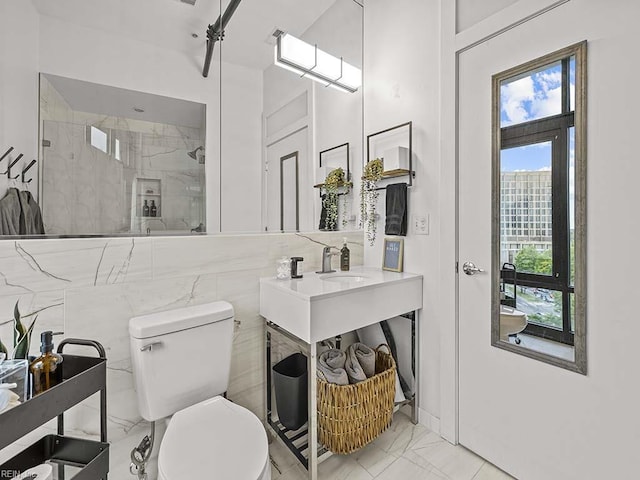 bathroom featuring sink, a shower with shower door, tile walls, and toilet