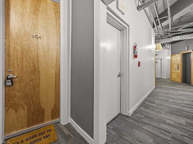 corridor featuring elevator and dark colored carpet