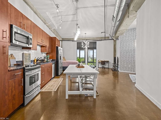 kitchen featuring a kitchen bar, track lighting, stainless steel appliances, decorative light fixtures, and a kitchen island