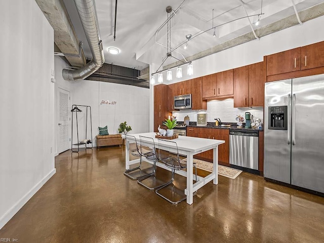 kitchen with sink, rail lighting, hanging light fixtures, a high ceiling, and appliances with stainless steel finishes