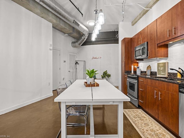 kitchen featuring track lighting, stainless steel appliances, sink, decorative light fixtures, and a kitchen island