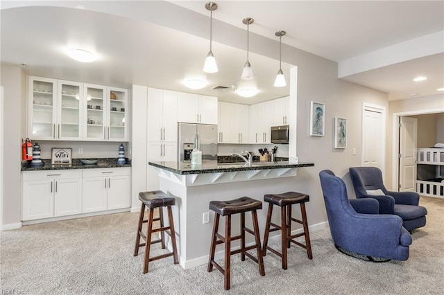 kitchen featuring white cabinetry, light colored carpet, decorative light fixtures, and appliances with stainless steel finishes